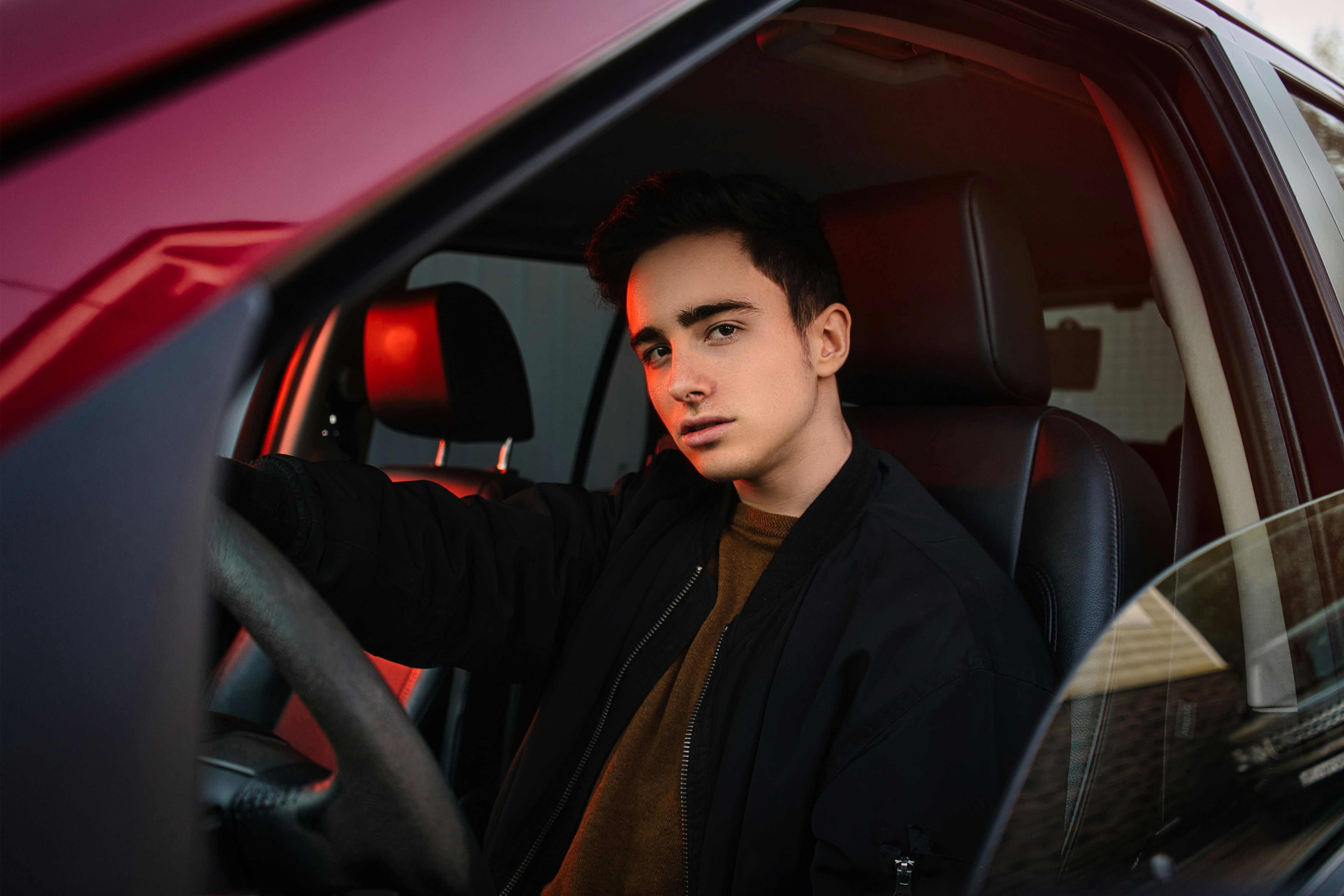 man in black suit jacket sitting on car seat